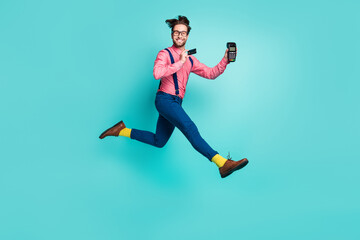 Fototapeta na wymiar Photo of sweet pretty guy dressed pink shirt spectacles holding credit card atm jumping high isolated turquoise color background