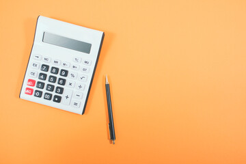 calculator and pen on orange background