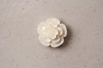 Fototapeta na wymiar A flower brooch made of natural white mother-of-pearl lies on a light modern gray white concrete background. Jewelry for women on a light background