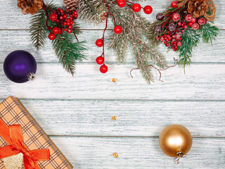 Christmas festive background of fir branches, balls and boxes on vintage boards.