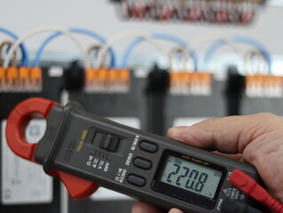 Voltage measurement using a multimeter in an electrical panel.