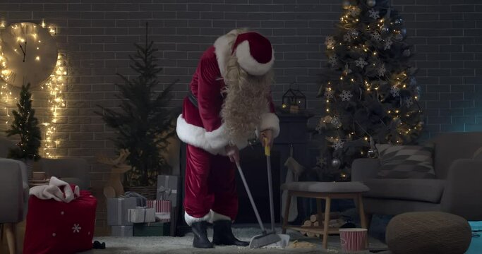 Santa Claus cleaning messy living room in evening