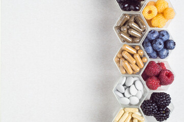 Fresh berries, pills and capsules in honeycomb like hexagonal jars