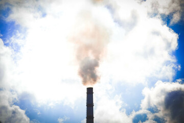 top tube factory with smoke from it against the sky with a bright sunlit white clouds, filter