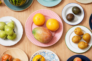 Top view image of plate set with assorted fruits, watermelon, grapefruit, African mangoes, ripe avocados, pink tomatoes, pears and bananas
