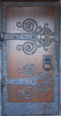 Old wooden doors of the monastery with a decorative metal hinges. Door of the church with carvings.