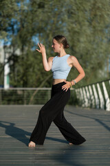 The girl dances beautifully on the embankment of the lake