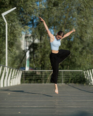 Fototapeta na wymiar The girl dances beautifully on the embankment of the lake