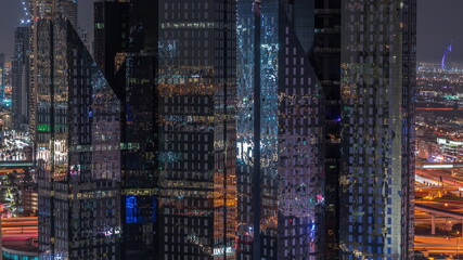 Glowing windows in office towers with glass surface in financial district of Dubai city timelapse.