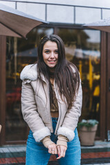 Fototapeta premium Beautiful smiling woman with long hair wearing warm jacket walk down street Warm european winter.