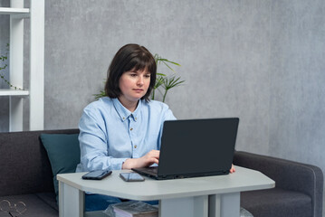 Girl works at laptop in living room. Freelance concept, work from home, remote work. Business woman.