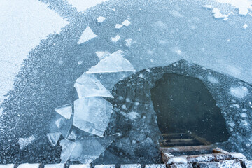 a high angle view of an ice hole for icy bathing near a footbridge ladder