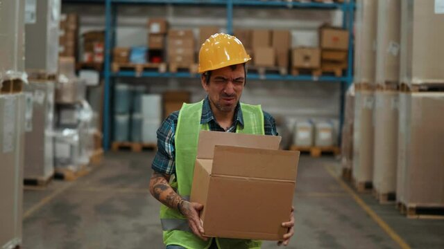 Exhausted warehouse worker having heart attack in storehouse falls down, chest pain.  Old warehouse worker gives first aid to his colleague lying on the floor