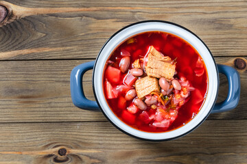 Rustic traditional borscht in pot on dark wooden background. Top view, copy space.