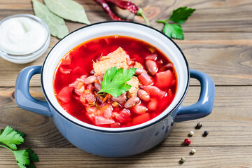 Traditional soup with beets beans beef borscht in pot on dark wooden background. Top view, copy space.