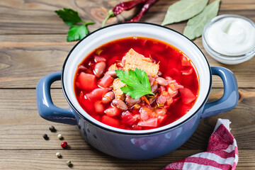 Traditional soup with beets beans beef borscht in pot on dark wooden background. Top view, copy space.