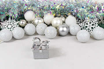 Silvery gift boxes on a blurred background with white and silver balls, garland and tinsel....
