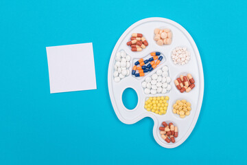 Global Pharmaceutical Industry and Medicinal Products - Different Colored Pills, Tablets and Capsules on White Art Palette with Blank Sticky Note and Copy Space Lying on Blue Background, Flat Lay