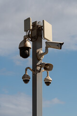 A group of CCTV cameras and a speaker on a metal pole in the street