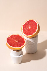 Grapefruit in calming coral colors in white stands and podiums. Сonceptual creative still life, peachy pastel colors, hard shadows, pop-art style. Healthy food concept