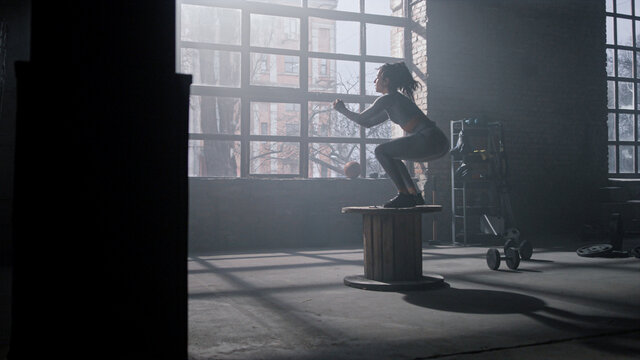 Woman using wooden box for training. Girl doing set of box jumps exercises