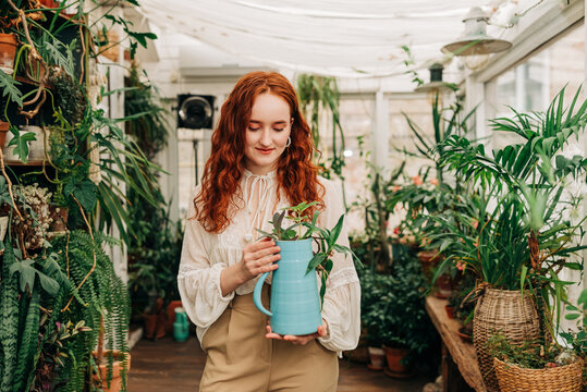 Gentle woman with jug of seedling in indoor garden