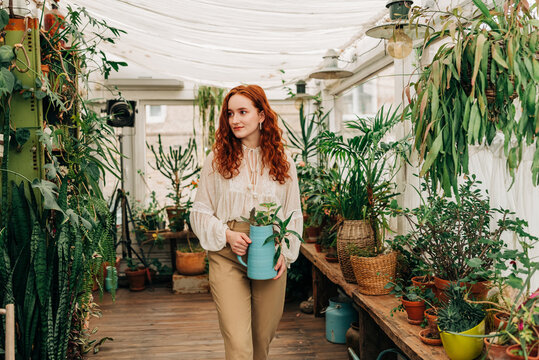 Gentle woman with jug of seedling in indoor garden