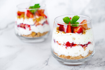 Strawberry dessert with cream cheese or yogurt, granola and fresh strawberry in glass on marble...