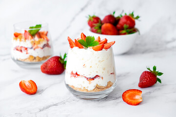 Strawberry dessert with cream cheese or yogurt, granola and fresh strawberry in glass. Festive layered dessert in glass. Vegan lactose free dessert with alternative nut milk.