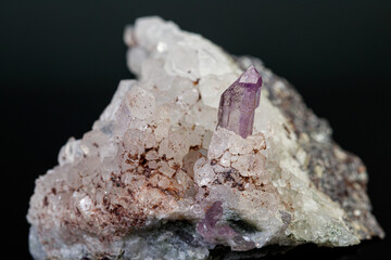 macro mineral amethyst stone in rock on a black background