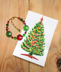Handmade glass bead bracelet and New Year's card with a decorated fir tree, New Year's composition, New Year's gifts, selective focus, vertical orientation.