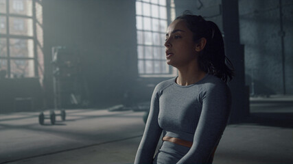Woman sitting on floor during fitness training in gym. Athlete breathing heavy