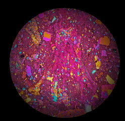 Colored sphere, with vibrant colors in shades of dark pink. Crystal seen under the microscope. Top view, abstract background. Black background.