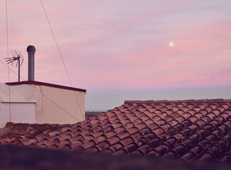 View of the moon at sunset from the roofs of buildings in the city