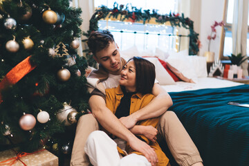 Multiracial couple between bed and christmas tree