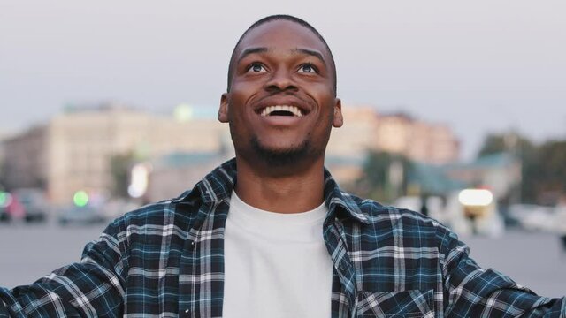 African American happy young guy in casual t-shirt isolated in city street outdoors looking at camera shocked surprised emotions wow showing hands brain explosion head gesture idea problem concept