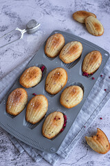 homemade cookies: madeleine cookies with raspberry slices in a white chocolate glaze on a gray background