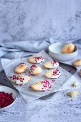 homemade cookies: madeleine cookies with raspberry slices in a white chocolate glaze on a gray background