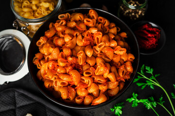 Pasta with tomato sauce on dark background.