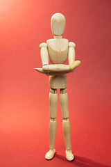 Wooden mannequin  staying with crossed hands, arms, picture on red background