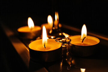 an engagement ring placed on the table between burning candles and a glass of champagne