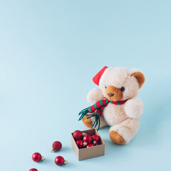 Creative arangment with Christmas bear and red baubles on blue background. Minimal New year concept. Retro aesthetic style.