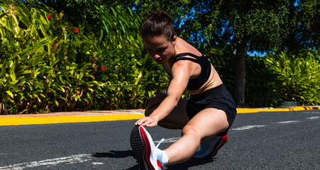 Adult 34-years old White, Caucasian Ethnicity athletic woman doing sport exercises outdoors in a tropical climate. Woman stretching before running.