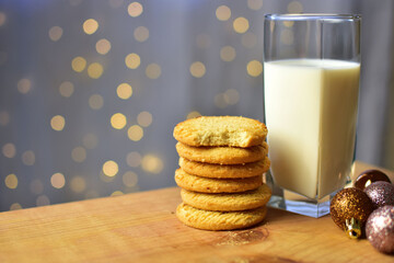 Vaso de leche y galletas con fondo de luces y esferas navideñas