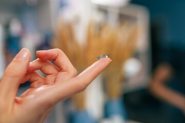 Transparent contact lens in the hands of a woman, preparing to insert it in her eyes