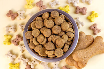Top view of brown biscuit bones and crunchy organic kibble pieces for dog feed on light background. Healthy dry pet food concept.