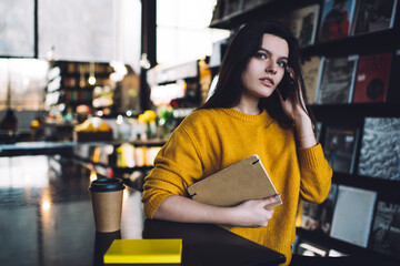 Focused young woman talking on smartphone in cozy bookstore