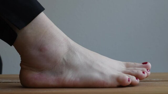 Person with a sprained ankle grabbing bandage roll to wrap around the swollen foot. 