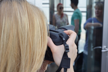 Young woman photographer taking photos outdoor on digital camera at a daytime