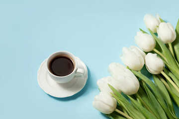 Cup of coffee and white tulips on a blue background